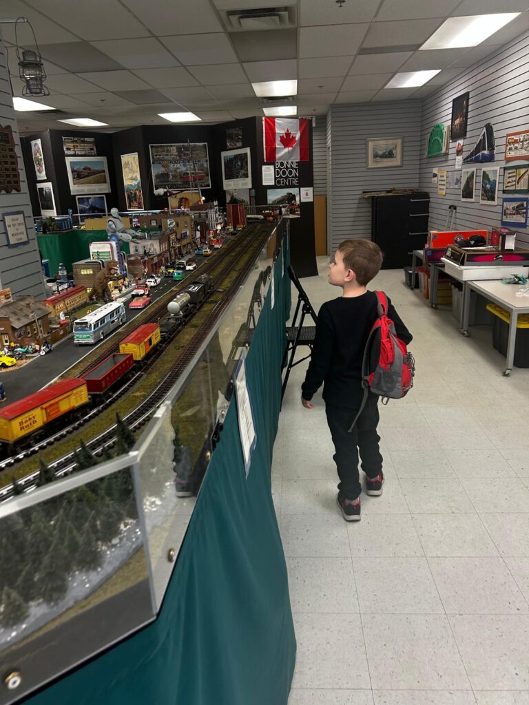 A child with a backpack walking past a large model train display