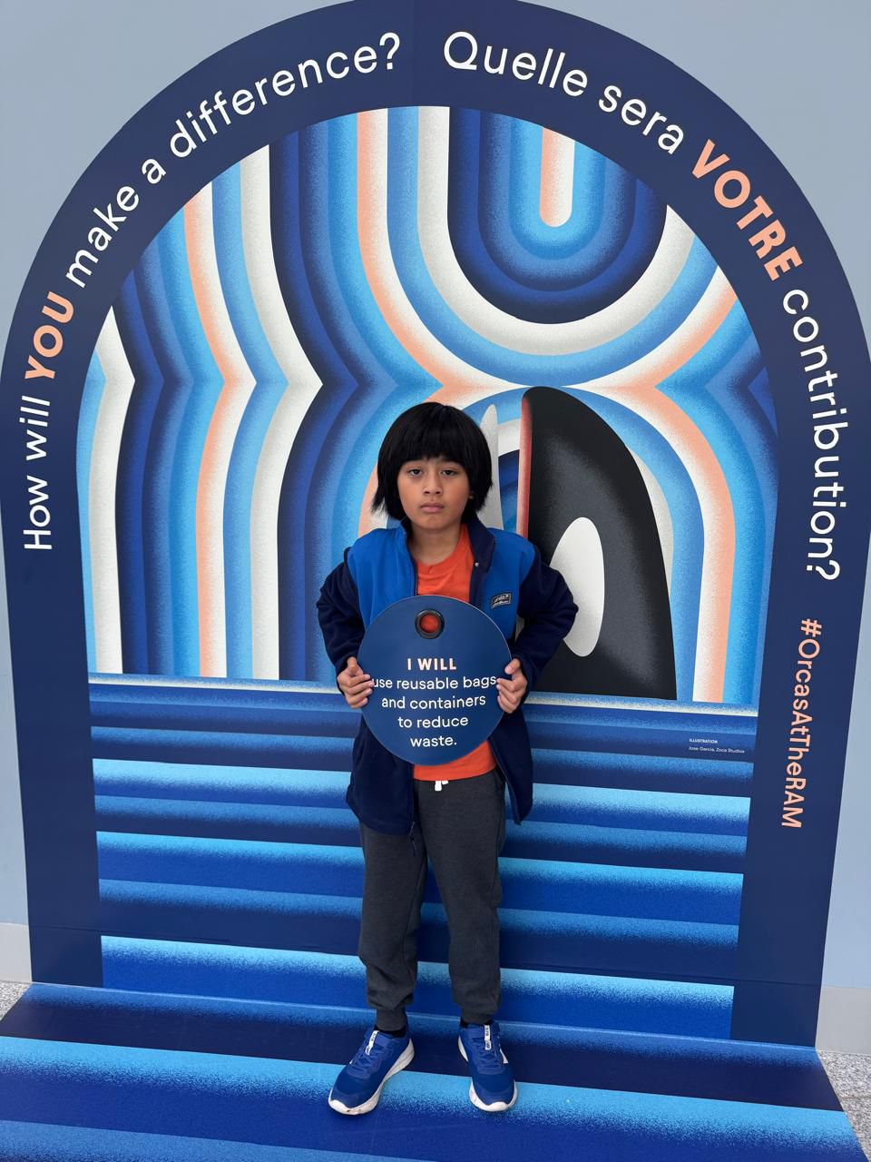 A child standing in a colourful museum exhibit arch that asks "How will you make a difference?"