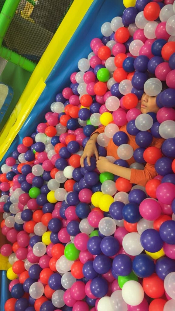 A child playing in a ball pit full of colourful balls